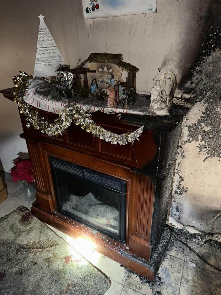 Soot-covered fireplace and wall after fire, decor items on mantel intact