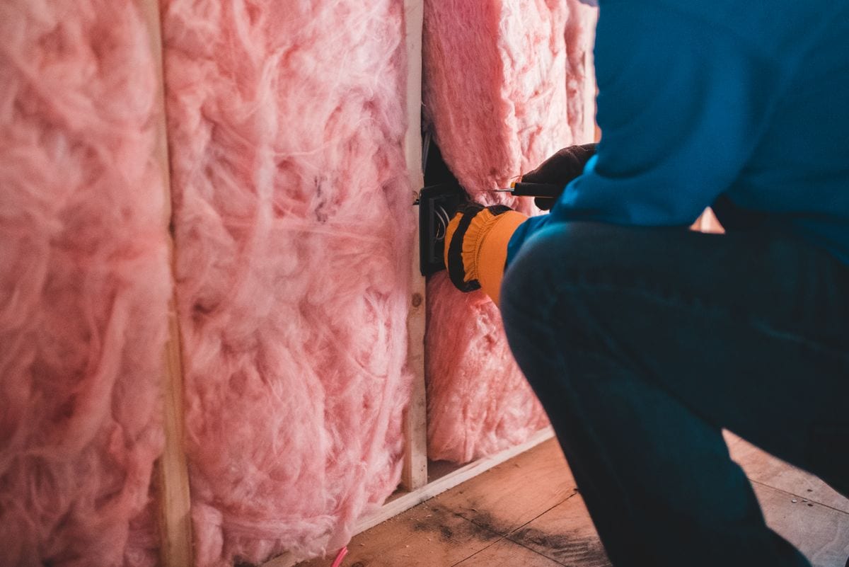 Worker removing old insulation material that may contain asbestos
