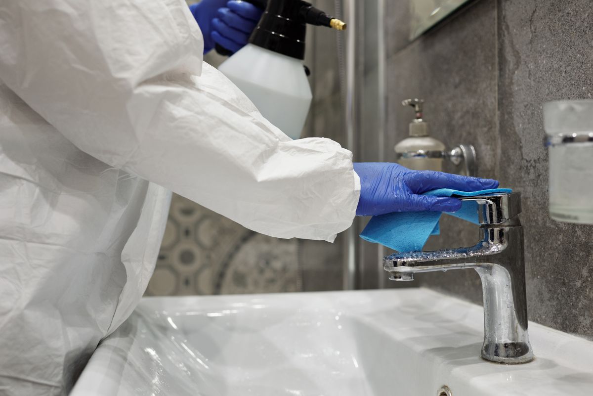 PPE Technician Disinfecting Surface Technician in PPE disinfecting a surface after biohazard cleanup